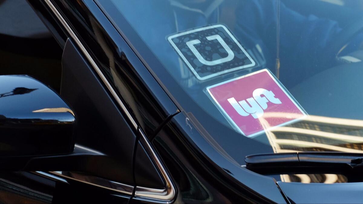 A driver displays Lyft and Uber stickers on his front windshield in downtown Los Angeles.