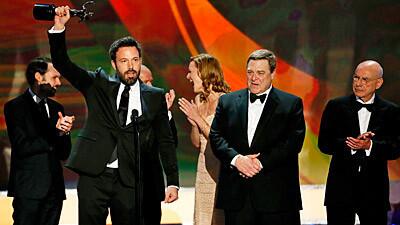 Surrounded by "Argo's" actors, Ben Affleck hoists the statuette that they won for cast performance.