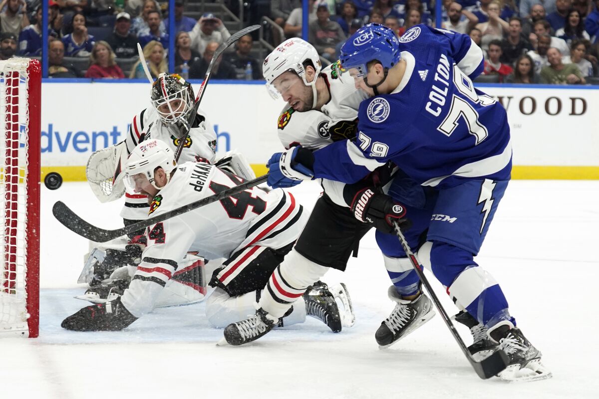 Tampa Bay Lightning center Ross Colton (79) gets off a shot as he battles with Chicago Blackhawks center Tyler Johnson (90), and defenseman Calvin de Haan (44) during the second period of an NHL hockey game Friday, April 1, 2022, in Tampa, Fla. (AP Photo/Chris O'Meara)