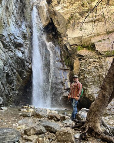 A person stands on rocks next to Millard Falls.