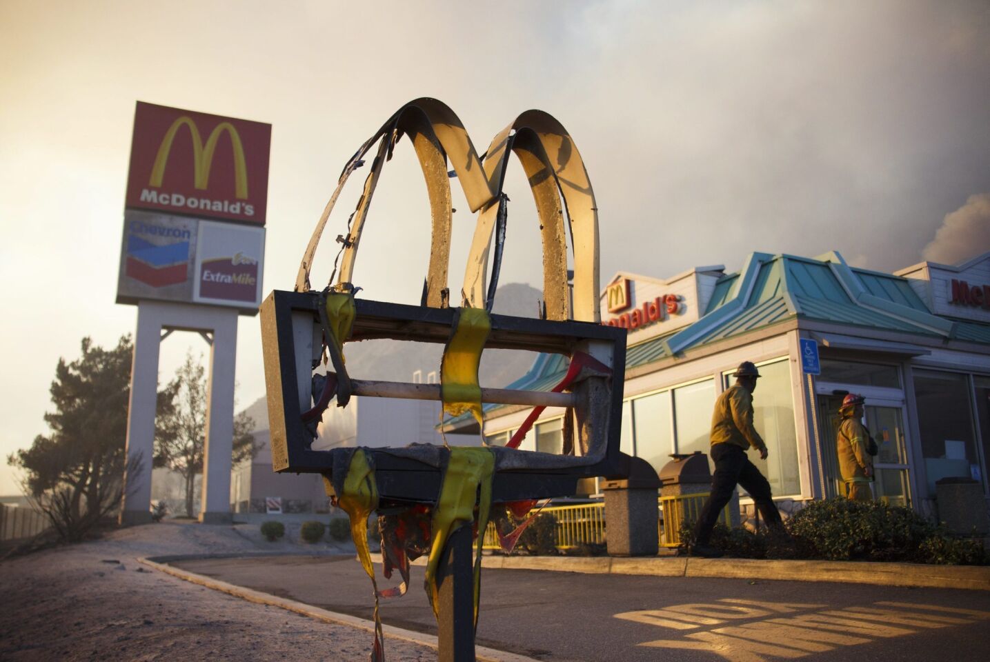 A melted sign from a McDonald's restaurant shows the damage as firefighters check the area after the Blue Cut fire swept through Cajon Junction.