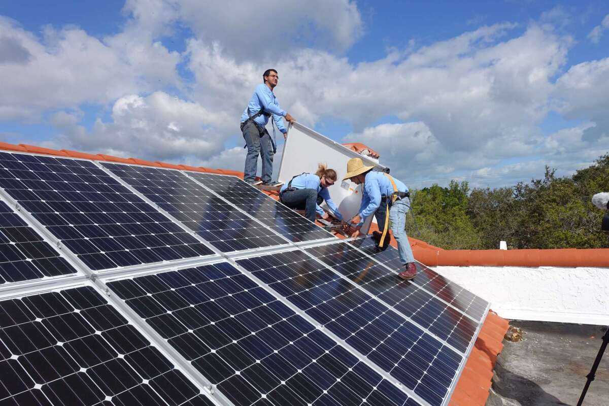 Workers install solar panels on a rooftop on Feb. 20 at a home in Palmetto Bay, Fla.