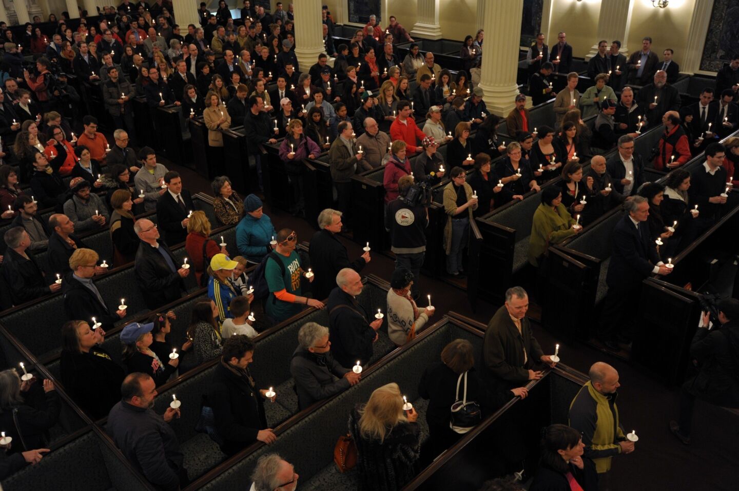 The congregation stands during a candlelight interfaith service Tuesday at Arlington Street Church in Boston for bombing victims.