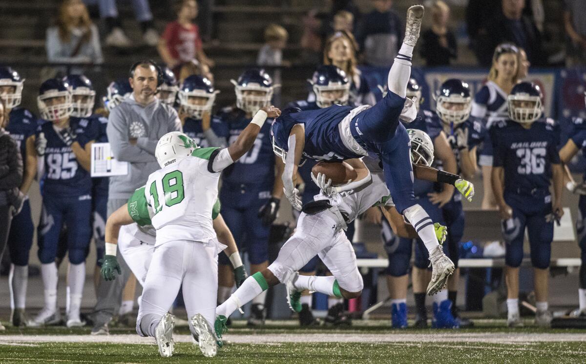 Newport Harbor's Justin McCoy gets upended on a tackle by Monrovia's Daylen Wilson in the quarterfinals of the CIF Southern Section Division 9 playoffs on Friday.