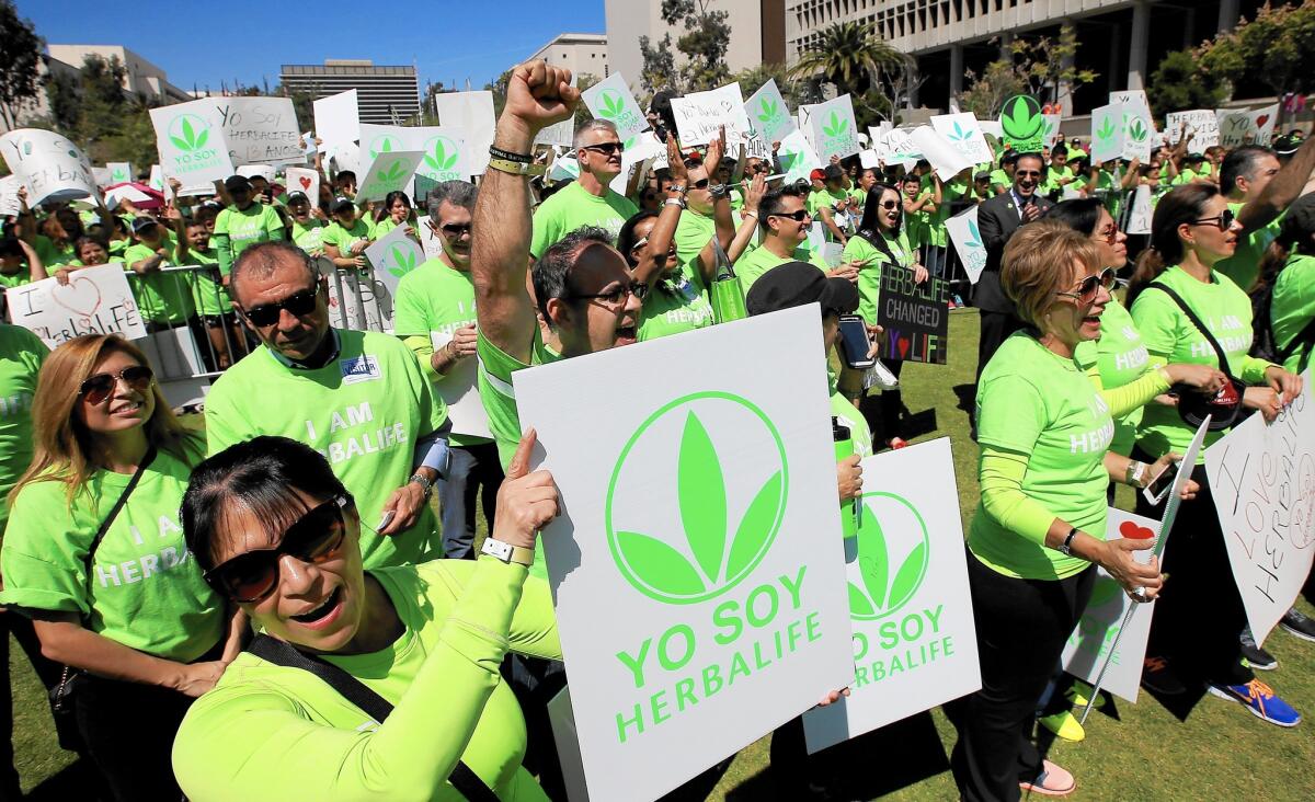 Hundreds of Herbalife distributors wearing green T-shirts gather at Grand Park in downtown Los Angeles to show their support for the beleaguered nutritional products company.