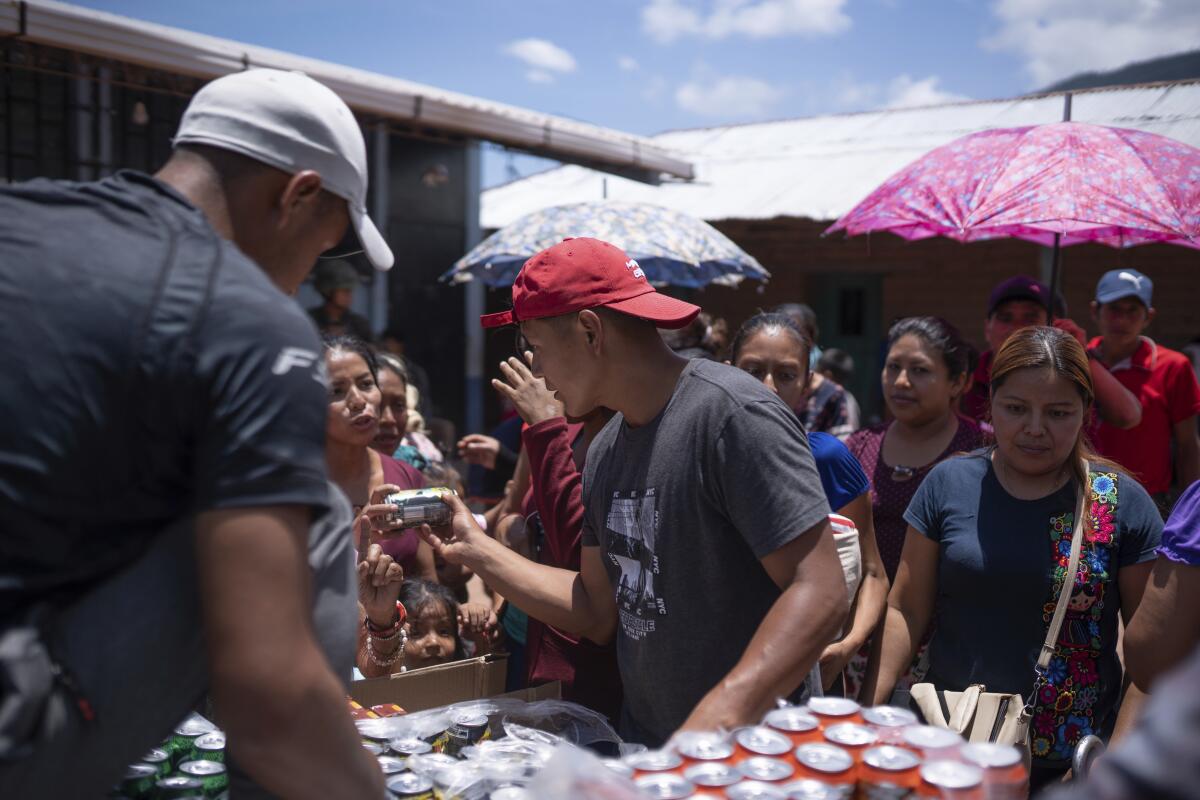 Lugareños en Guatemala ofrecen refrescos a los mexicanos que huyeron de su pueblo de Amatenango, México, 
