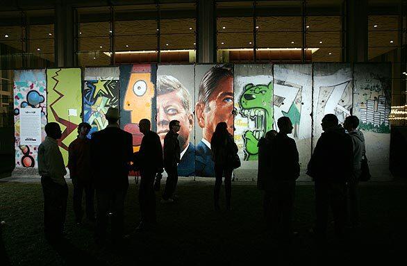 Visitors take in the "Wall Along Wilshire -- Eastside Gallery West," a 40-foot section of the original Berlin Wall that is on view at the 5900 Wilshire Blvd. building through Saturday. Sections of the wall feature paintings by Los Angeles muralist Kent Twitchell and Berlin-based Thierry Noir.