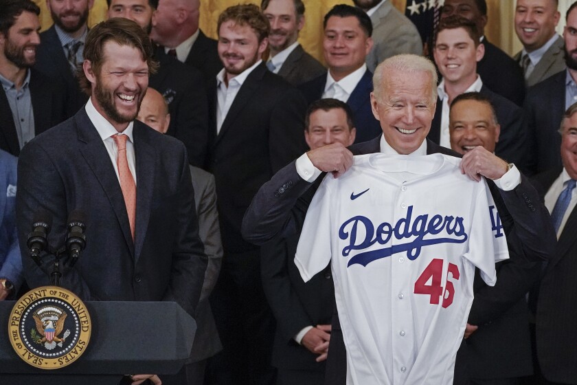 Clayton Kershaw laughs as President Joe Biden holds up a jersey gifted to him.