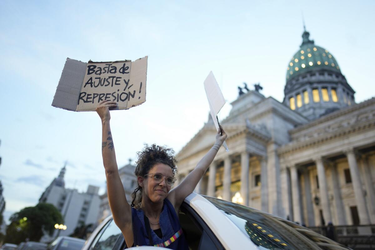 Una mujer se asoma por la ventana de un vehículo sosteniendo carteles de rechazo