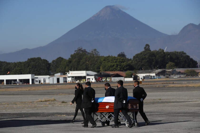 People transport a flag-draped coffin on the runway as the remains of 16 Guatemalan migrants who were killed near the U.S.-Mexico border in January arrive at the Air Force base in Guatemala City, Friday, March. 12, 2021. The migrants were among 19 people shot and burned in Camargo, located in the northern Mexican state of Tamaulipas on Jan. 22. Five people survived. (AP Photo/Moises Castillo)