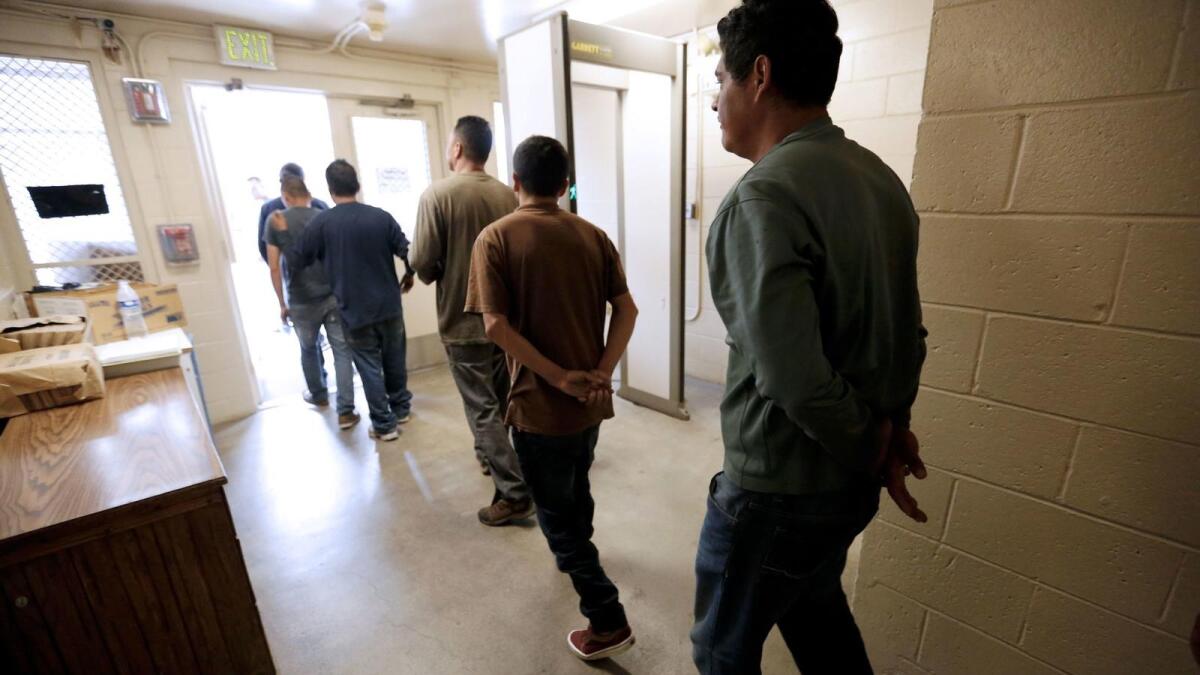 Immigrants are led to a van destined for U.S. Immigration and Customs Enforcement after being processed at the Chula Vista Station.