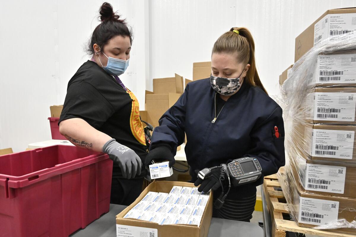 Employees with the McKesson Corporation scan a box of the Johnson & Johnson COVID-19 vaccine