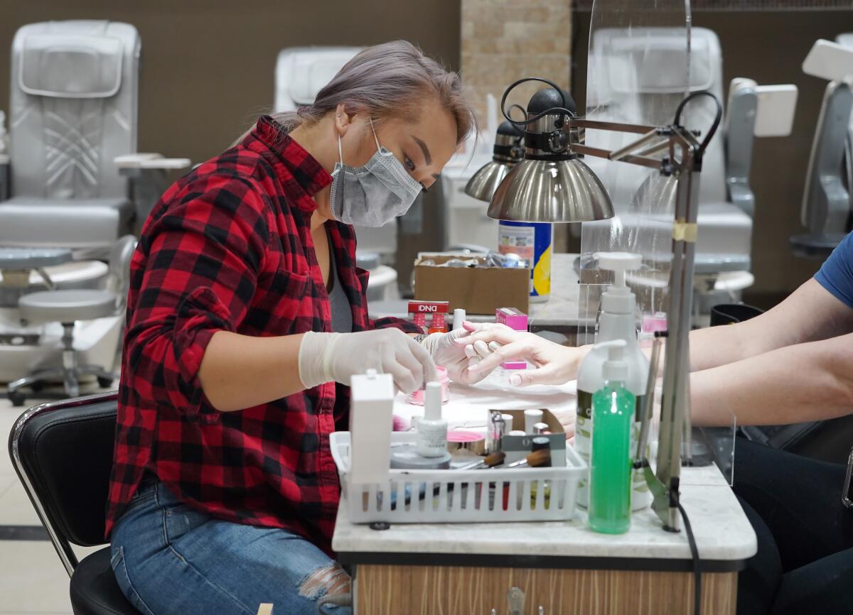 Debi Dang works on the nails of a customer at Allure Nail Bar in Atlanta, Georgia. Governor Brian Kemp has eased restrictions allowing some businesses such as hair and nail salons to reopen.