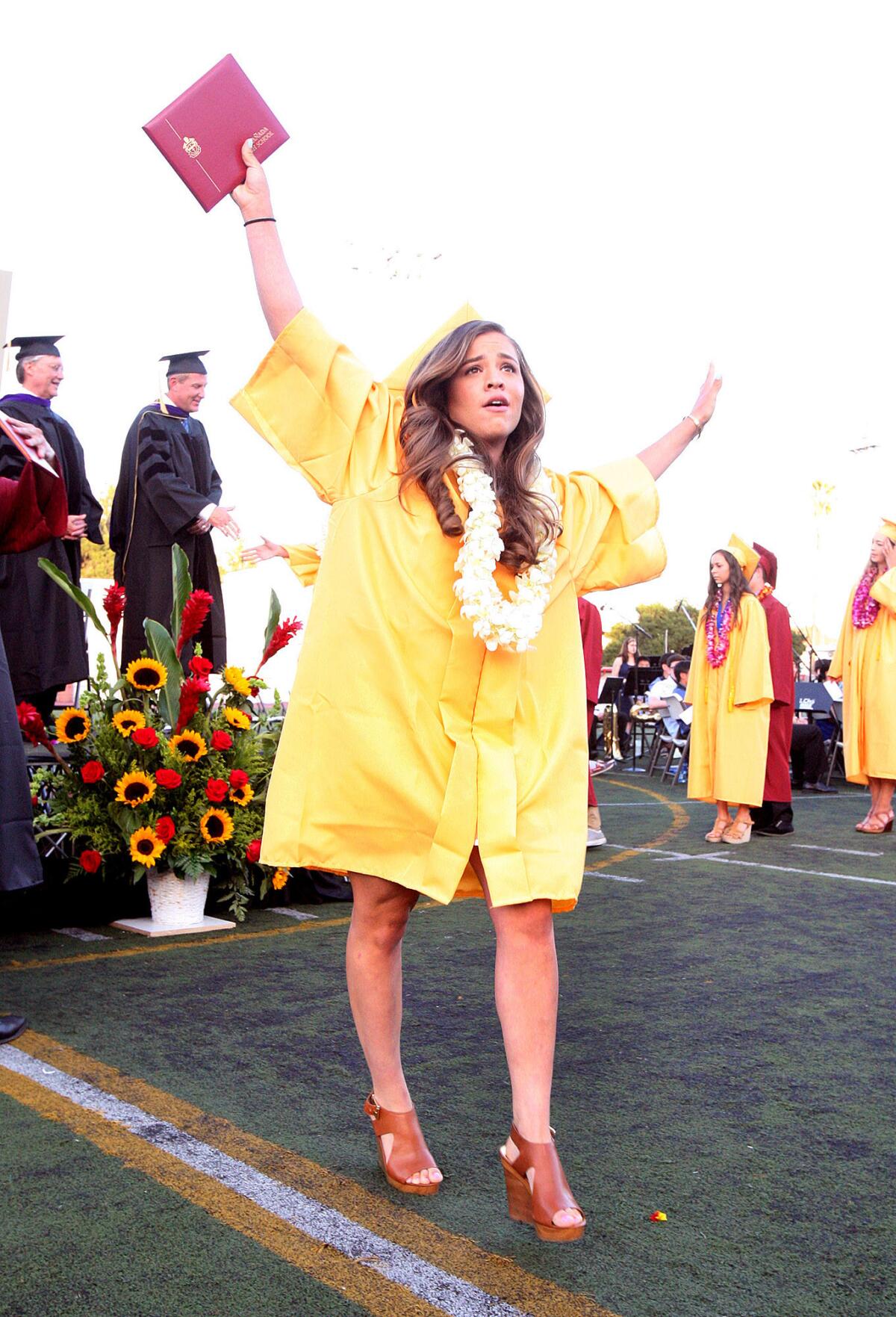 Graduate Taylor Afshar proudly lifts her diploma over her head after graduating at the graduation of La Canada High School on the football field in La Canada Flintridge on Thursday, June 5, 2014.