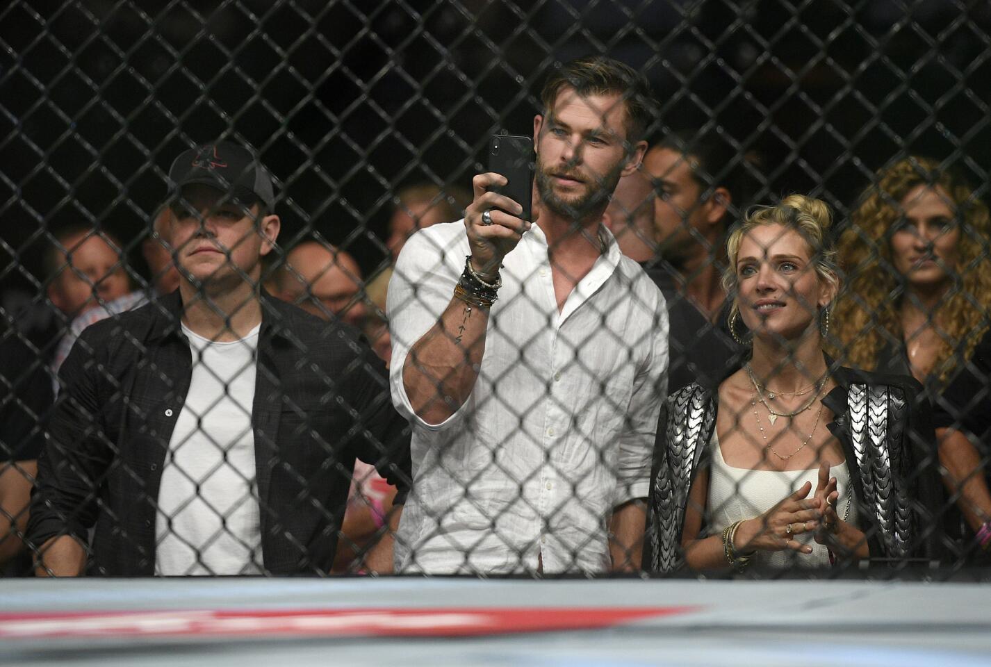 Actors, Matt Damon, left, Chris Hemsworth, center, and his wife Elsa Pataky watch Nigeria's Israel Adesanya and Brazil's Anderson Silva during their middleweight bout at the UFC 234 event in Melbourne, Australia, Sunday, Feb. 10, 2019. (AP Photo/Andy Brownbill)