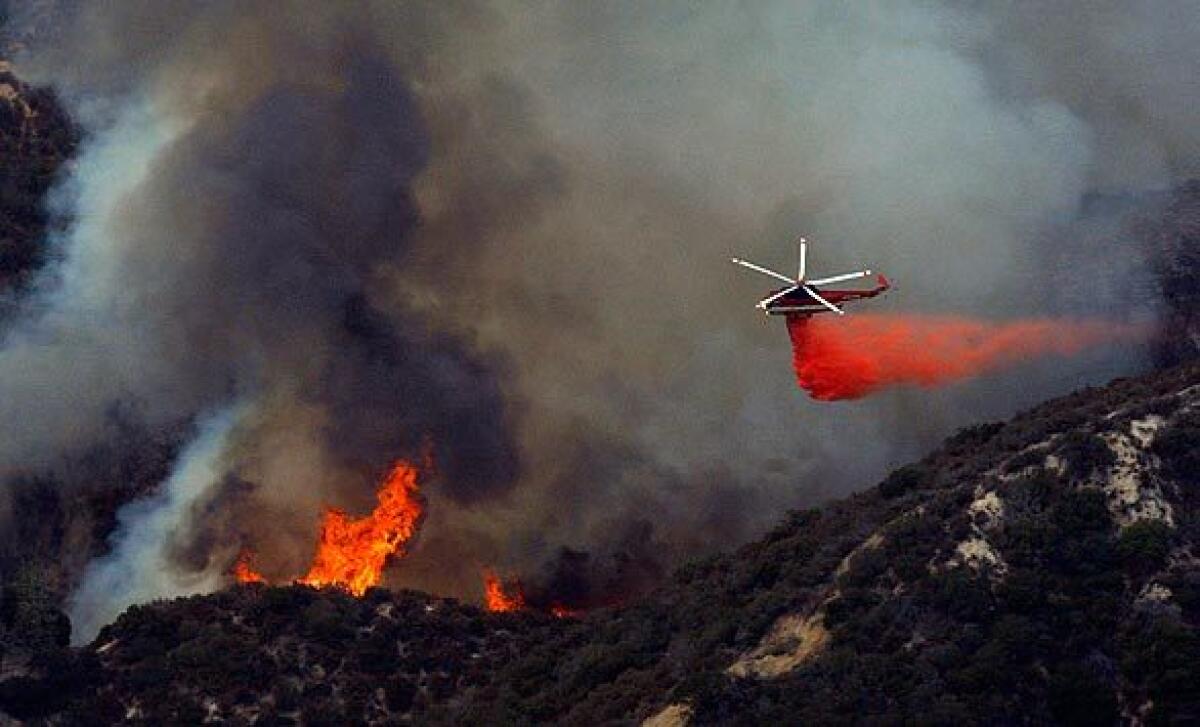 A helicopter drops fire retardant on a part of the Station fire burning close to homes in Tujunga's Blanchard Canyon.