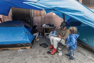 LOS ANGELES, CA - APRIL 25: Jhon (cq) Valencia plays with Thian, 2, with his mother Katherine Gonzalez in the back, on Towne Avenue in Skid Row. The county has said it was addressing the problem of families on the street and had the resources to house all families immediately but that has not happened. Photographed on Skid Row in Los Angeles, CA on Thursday, April 25, 2024. (Myung J. Chun / Los Angeles Times)