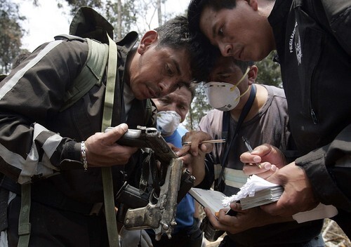 An Ecuadorean police forensic team examines pistols that were found at a camp of the Revolutionary Armed Forces of Colombia, or FARC, where Colombian forces killed a senior rebel leader and 16 other guerrillas.