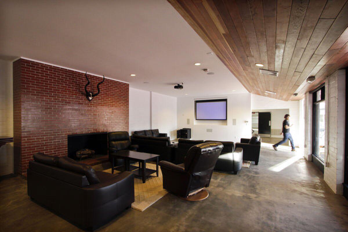 Inside the remodeled frat house, larger windows let in more natural light and cedar ceiling paneling lends a modern touch. Because durability was a primary concern, the design team replaced worn carpeting with a concrete floor, and upstairs, space-saving loft beds are framed in metal.