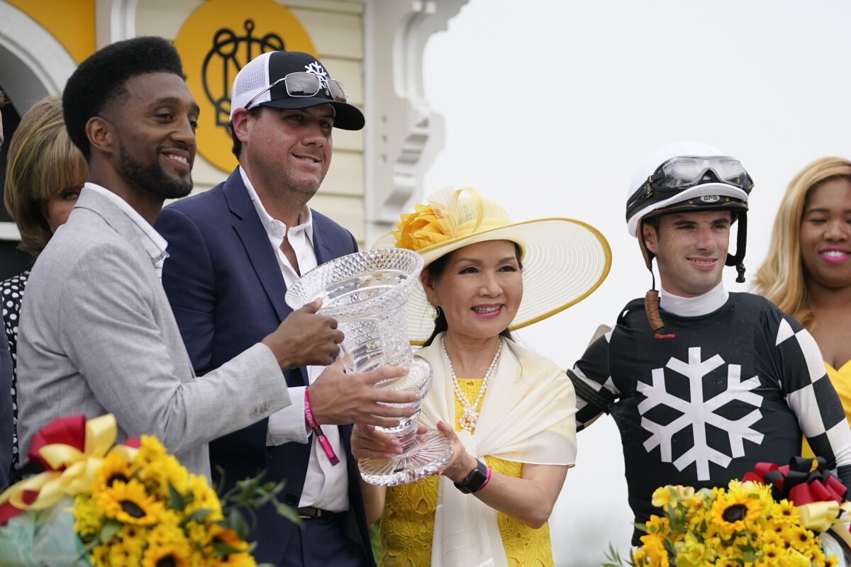 Four people stand with a loving cup in the winner's circle