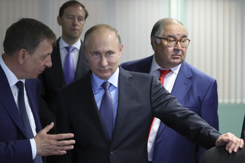 FILE - Russian President Vladimir Putin, center, listens to Lebedinsky GOK Managing Director Oleg Mikhailov, left, as businessman and founder of USM Holdings, Alisher Usmanov, right, and Minister of Industry and Trade Denis Manturov stand behind him while visiting the Lebedinsky GOK JSC, in Gubkin, Belgorod Region, Russia, Friday, July 14, 2017. Usmanov is not on the sanctions list implemented in response to the 2022 invasion of Ukraine. The metals tycoon was an early investor in Facebook. His fortune is estimated at more than $14 billion. (Mikhail Klimentyev/Sputnik/Kremlin Pool Photo via AP, File)