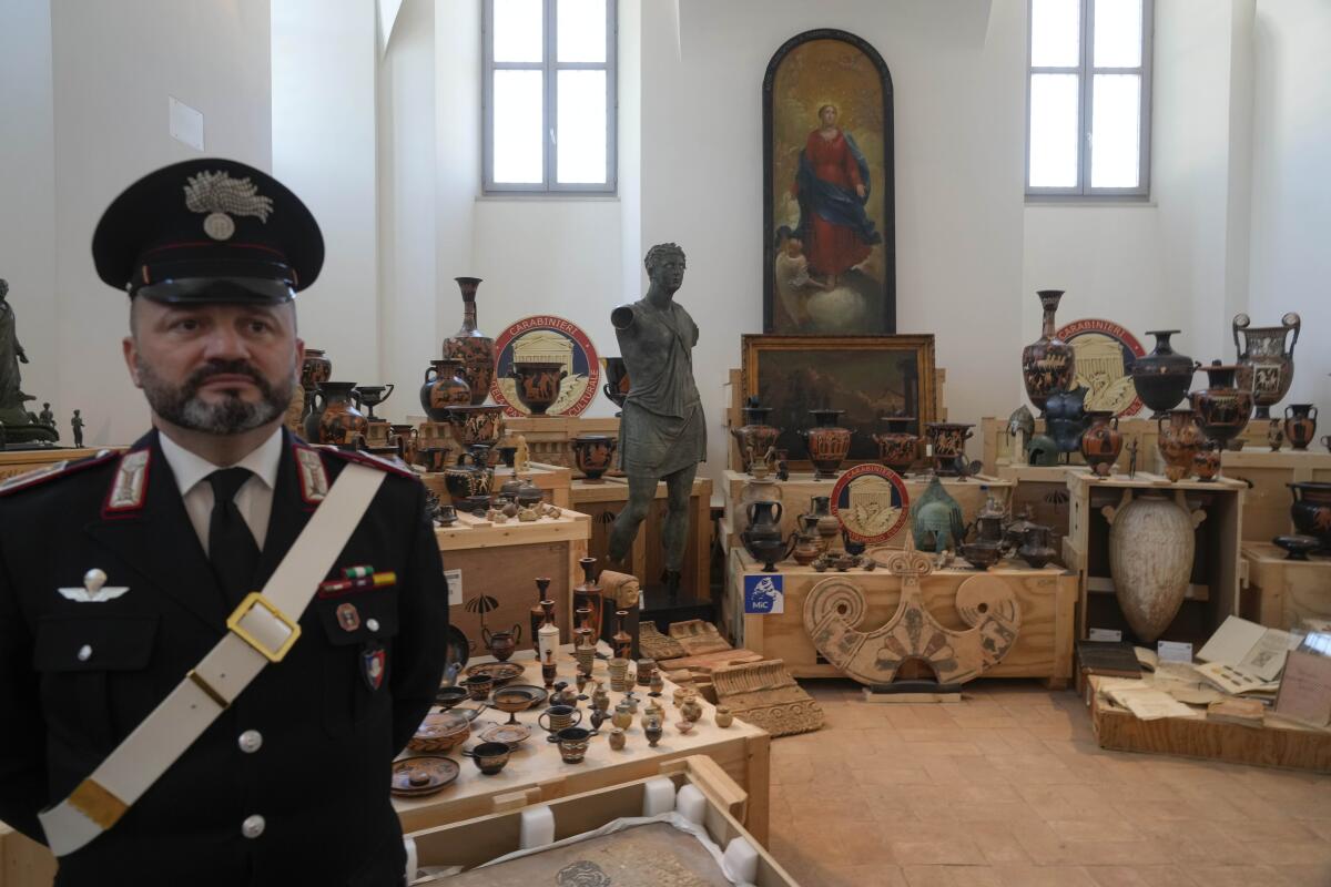 A uniformed guard stands before a room full of art and other artifacts 