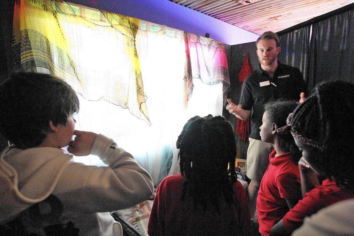 World Vision mobile experience field manager Nate Xanders talks to a group of students from Harambee Preparatory School visiting a nationally touring exhibit, "In the Margins:"which allows people see, hear and experience the lives of children across the world whose lives have been devastated by poverty.