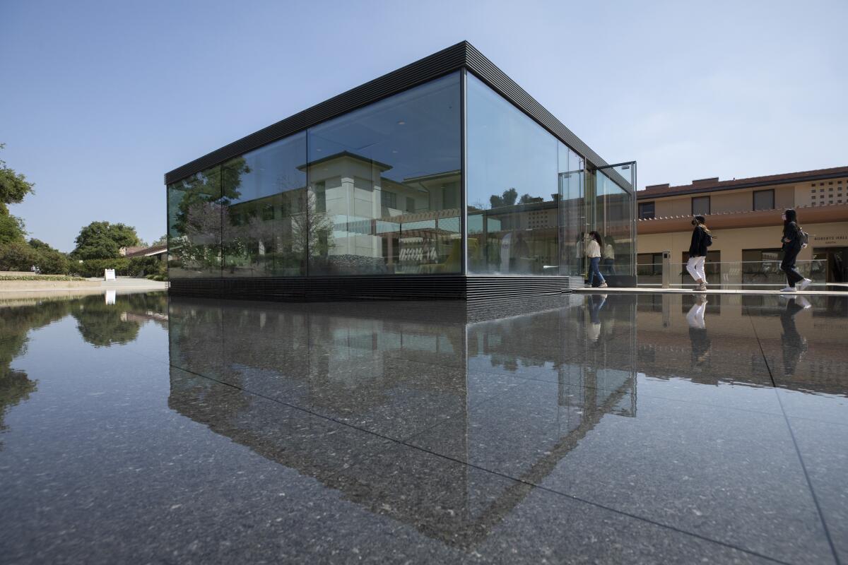 Prospective students enter a glass-enclosed building on a college campus. 