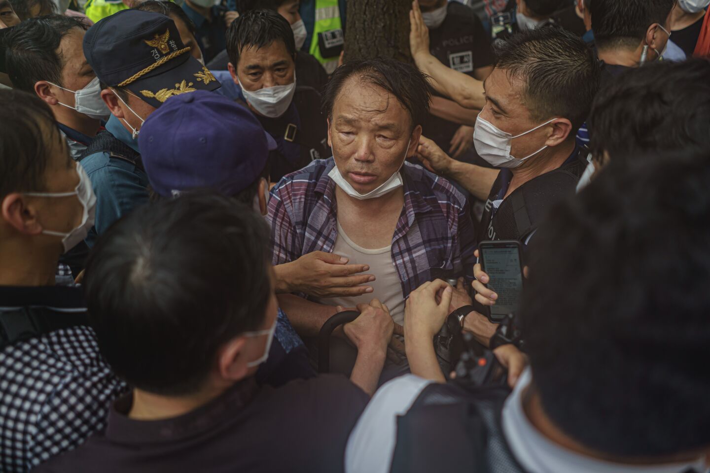 A protester is surrounded by police officers.