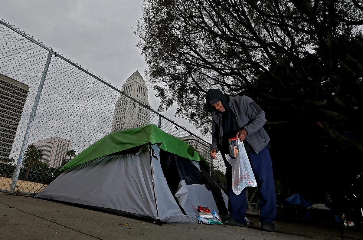 A homeless man brings snacks and toiletries back to his tent on First Street near Los Angeles City Hall.
