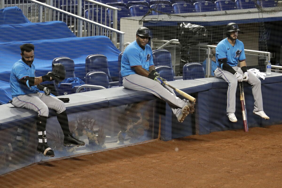 Miami Marlins teammates Jonathan Villar, Jesus Aguilar and Jon Berti wait to bat during a team scrimmage.
