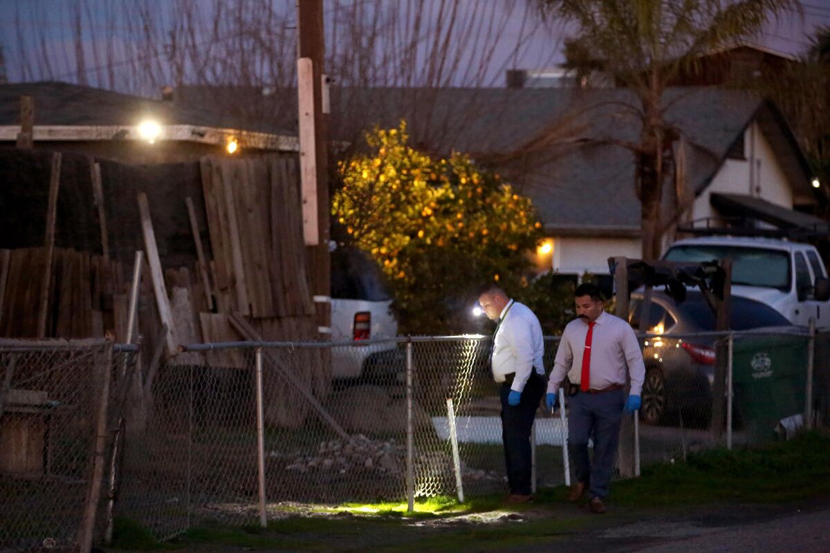Officials shine flashlights in a backyard.