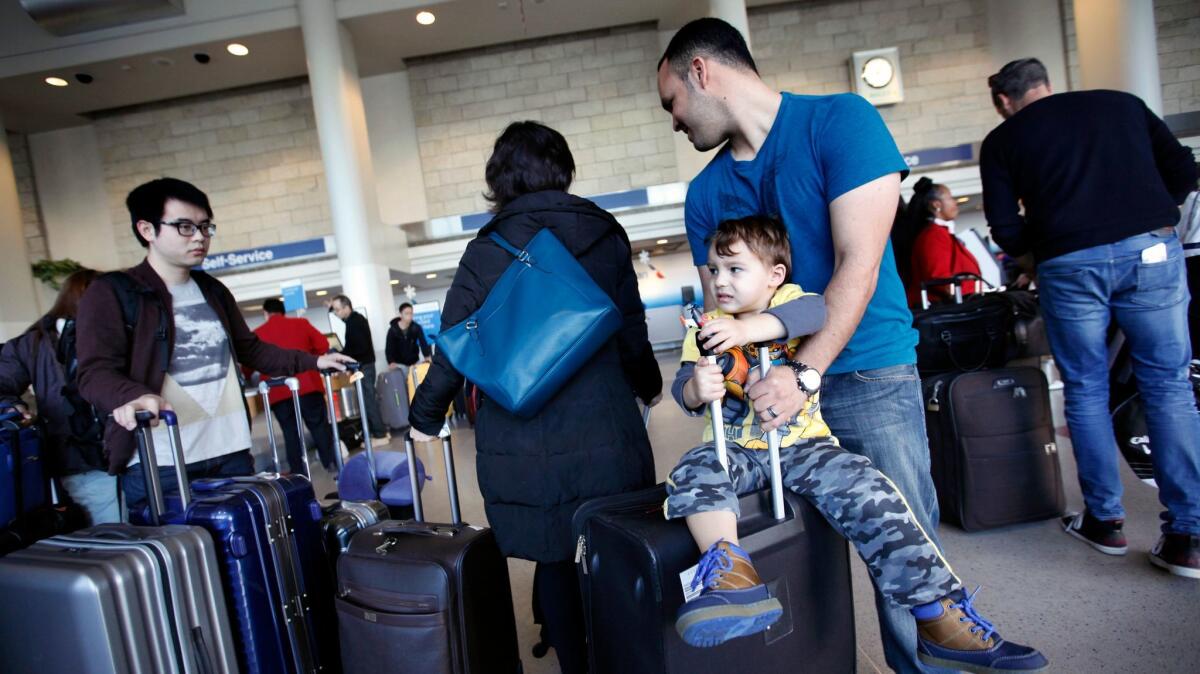 Idan Madhala and son Daniel wait in line at the American Airlines counter at Los Angeles International Airport on Christmas Eve 2014.