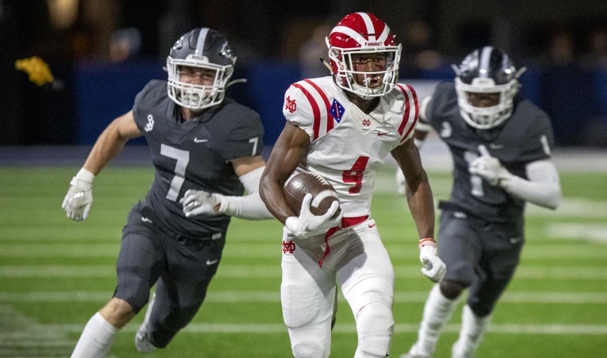 St. John Bosco free safety Jake Newman, left, and cornerback Josh Alford, right, pursue Mater Dei wide receiver Kody Epps.