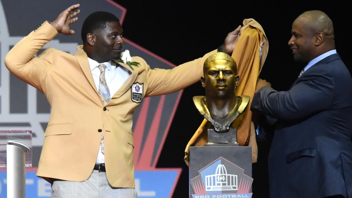 LaDainian Tomlinson, left, and his presenter, Lorenzo Neal, unveil his bust before his speech during the induction ceremony at the Pro Football Hall of Fame on Saturday.
