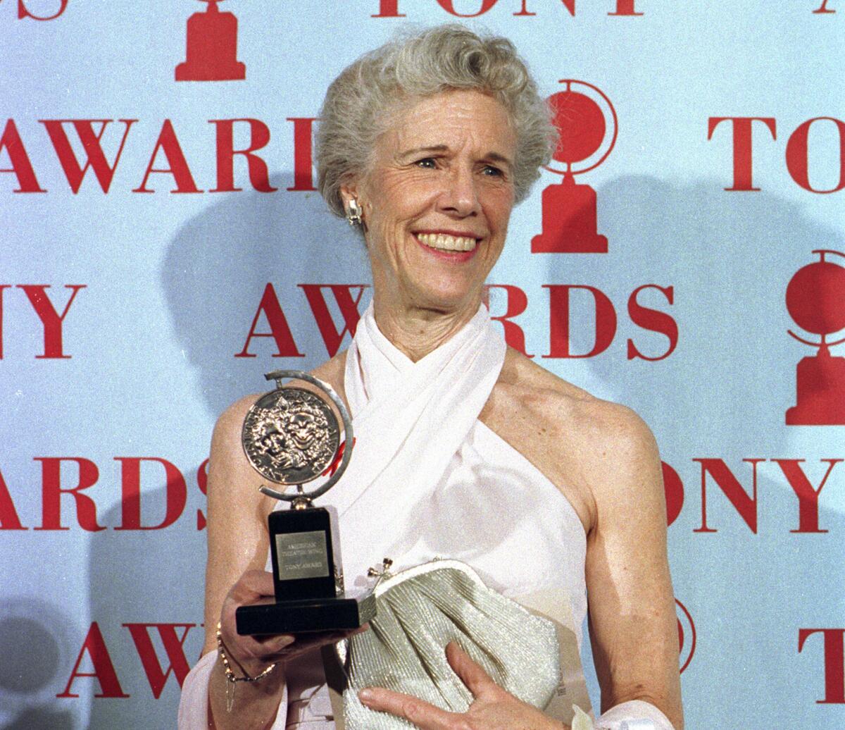 Frances Sternhagen, in a white halter gown, smiles and holds a Tony Award in one hand and a sparkling clutch in the other