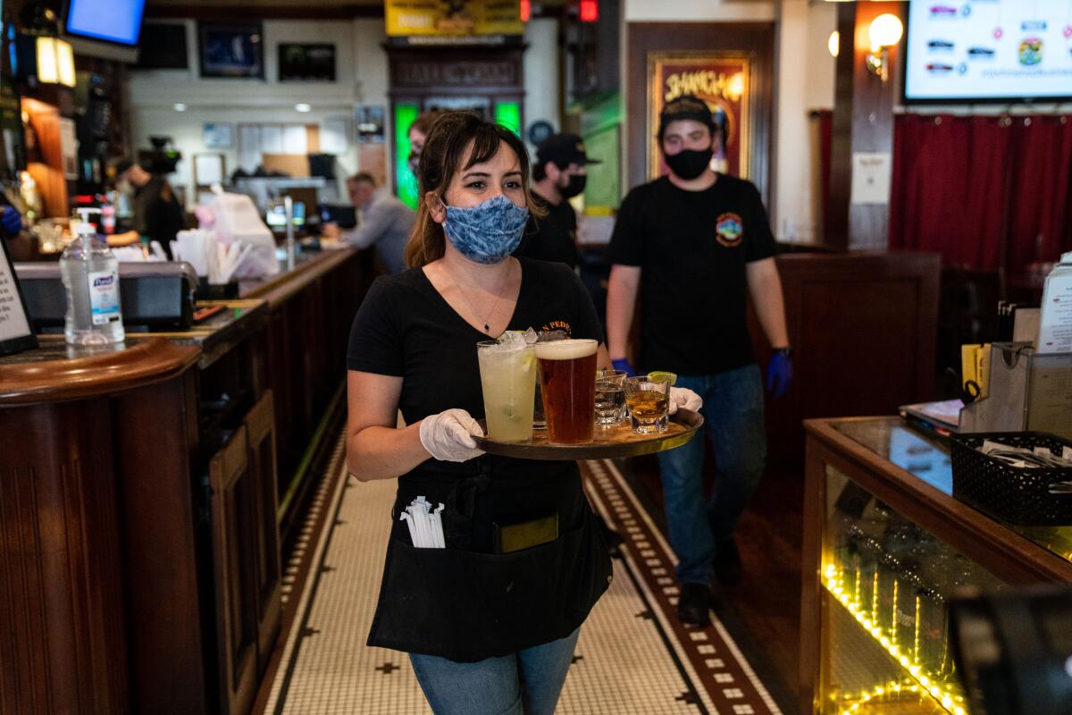 Sloane Sires carries drinks to customers dining in at the San Pedro Brewing Company on Friday.