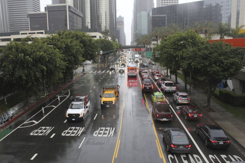A storm brings a rainy morning commute through downtown Los Angeles, Wednesday, March 29, 2023. A cold low pressure system spinning off the coast of California sent bands of rain and snow across the state Wednesday, making travel difficult and adding to an epic mountain snowpack. (AP Photo/John Antczak)