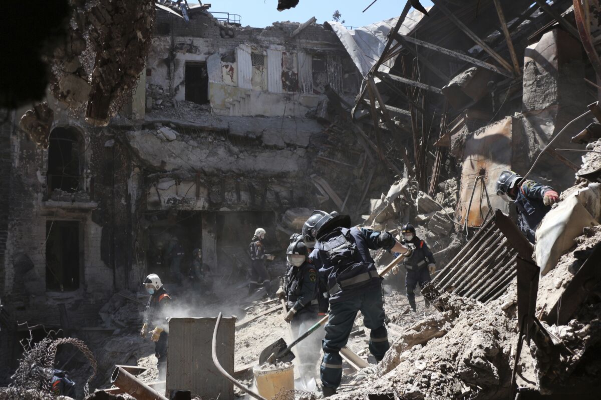 Donetsk People Republic Emergency Situations Ministry employees clear rubble at the side of the damaged Mariupol theater building during heavy fighting in Mariupol, in territory under the government of the Donetsk People's Republic, eastern Ukraine, Thursday, May 12, 2022. (AP Photo)