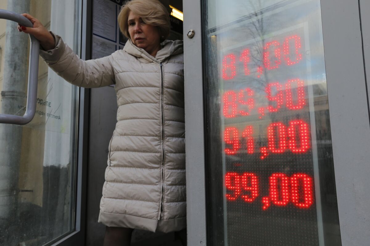 In this Feb. 24, 2022, photo, a woman leaves an exchange office with screen showing the currency exchange rates of U.S. Dollar and Euro to Russian Rubles in Moscow, Russia. The harsh sanctions imposed on Russia and the resulting crash of the ruble have the Kremlin scrambling to keep the country's economy running. For Russian President Vladimir Putin, that means finding workarounds to the economic blockade even as his forces continue to invade Ukraine. (AP Photo/Alexander Zemlianichenko Jr., File)