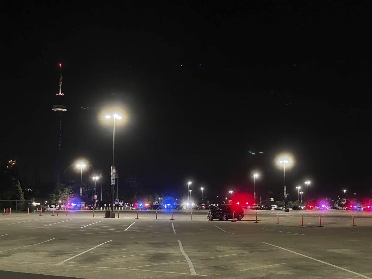 Emergency vehicles are shown in the parking lot of Six Flags Great America in Gurnee, Ill., Sunday night, Aug. 14, 2022. Three people were injured in a shooting in the parking lot that sent visitors scrambling for safety, authorities said. (Kaitlin Washburn/Chicago Sun-Times via AP)