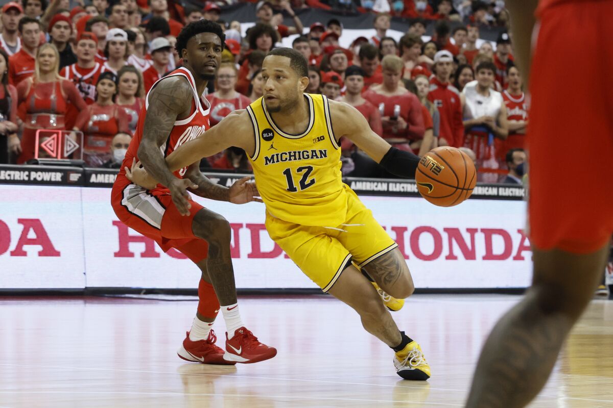 Michigan's DeVante Jones, right, dribbles up the court as Ohio State's Jamari Wheeler defends during the first half of an NCAA college basketball game, Sunday, March 6, 2022, in Columbus, Ohio. (AP Photo/Jay LaPrete)