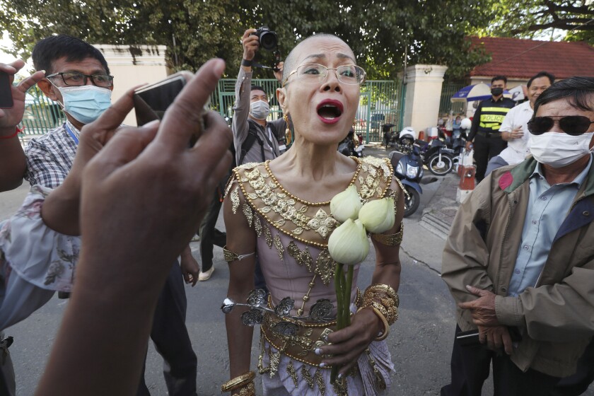 Theary Seng, a Cambodian-American lawyer, dressed in a traditional Khmer Apsara dance costume, speaks to media as she arrives to continue her trial in the municipal court in Phnom Penh, Cambodia, Tuesday, Dec. 7, 2021. Seng and over 40 other defendants charged with treason for taking part in nonviolent political activities were summoned back to court Tuesday to continue their trial that had been suspended since November 2020 due to the coronavirus. (AP Photo/Heng Sinith)