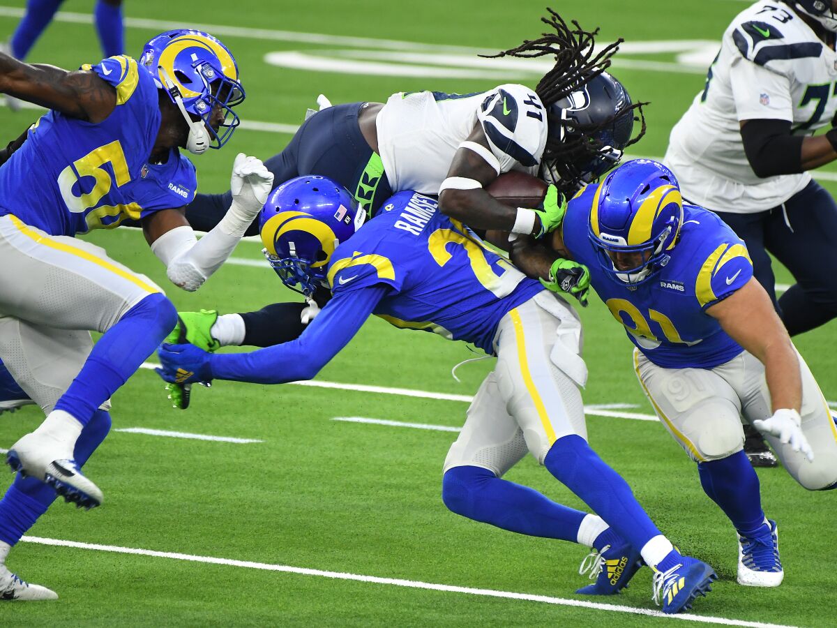 Seattle Seahawks running back Alex Collins is tackled by Rams cornerback Jalen Ramsey and defensive lineman Greg Gaines.