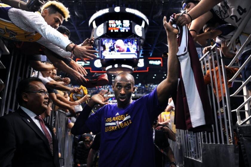 Kobe Bryant high-fives fans as he walks off the court for the last time in Phoenix after a game against the Suns on March 23.