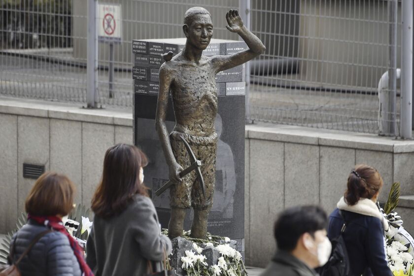 Varias personas pasan frente a una estatua que simboliza a los coreanos obligados a realizar trabajos forzados, el 6 de marzo de 2023, en Seúl. (Kyodo News vía AP)