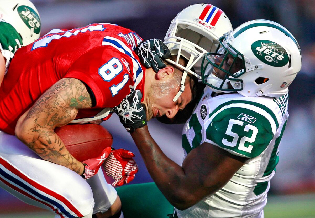 A football player, with his white helmet on his head, tackles another football player on the chest.