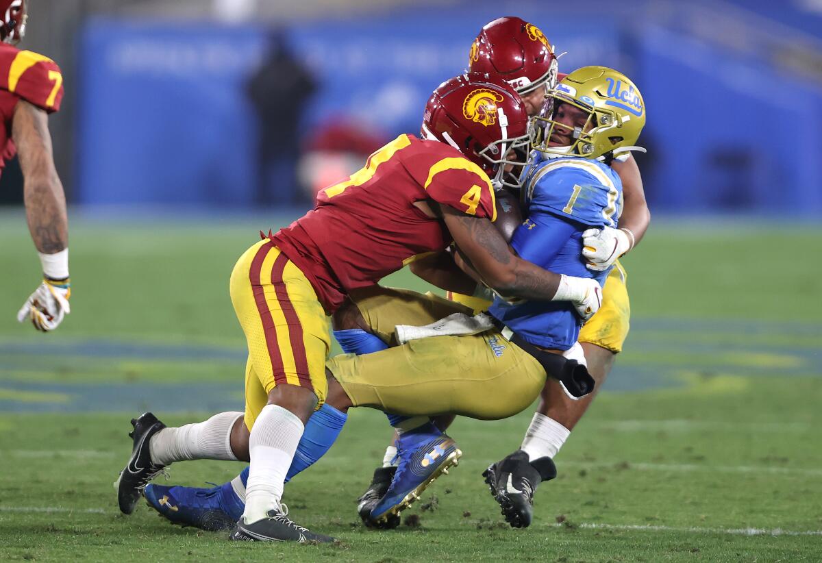 USC defensive back Max Williams (4) helps bring down UCLA quarterback Dorian Thompson-Robinson.