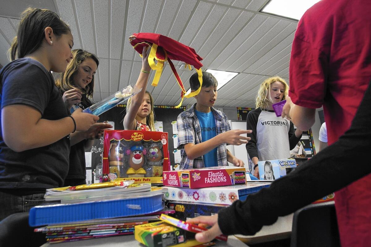 Students Rachel Rucknagel, 11, Bree Anderson, 12, Sydney Meunier, 11, Brodi White, 12, and Ruby Yuchytil, 11, from left, sort toys at Victoria Elementary School in Costa Mesa on Wednesday. The school is conducting a toy drive for Children’s Hospital of Orange County, where Sydney donated bone marrow to her younger brother in 2007.