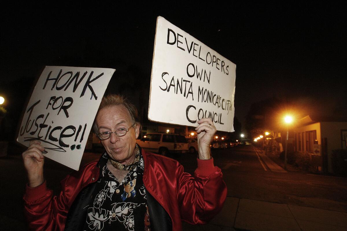 Peter Naughton, 63, holds protest signs in front of the Village Trailer Park in Santa Monica. He has lived in the park since 1991; his trailer home has been in his family since 1986.